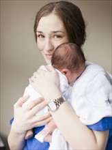 Portrait of young female nurse holding baby boy (2-5 months). 
Photo: Jessica Peterson