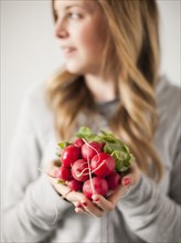 Portrait of attractive young woman holding radish. 
Photo: Jessica Peterson