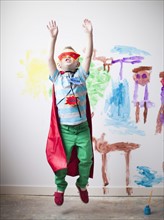 Toddler boy (2-3) in superhero costume jumping mid-air. 
Photo : Jessica Peterson
