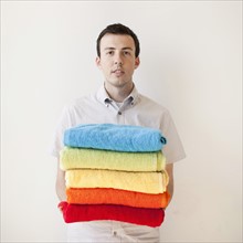 Young man holding stack of multi-coloured towels. 
Photo: Jessica Peterson