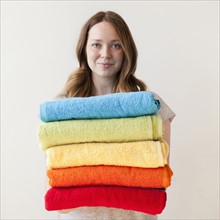 Young woman holding stack of multi-coloured towels. 
Photo: Jessica Peterson