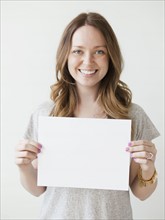 Portrait of serene young woman holding blank card. 
Photo : Jessica Peterson