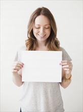 Portrait of cheerful young woman holding blank card. 
Photo: Jessica Peterson