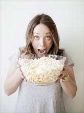 Young woman devouring bowl of popcorn. 
Photo : Jessica Peterson
