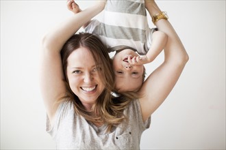 Young woman holding baby boy (6-11 months) upside-down. 
Photo : Jessica Peterson