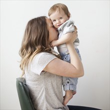 Portrait of young woman embracing baby boy (6-11 months). 
Photo: Jessica Peterson