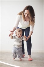 Young mother assisting baby boy (6-11 months) in first steps. 
Photo: Jessica Peterson
