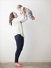 Young mother lifting baby boy (6-11 months) mid-air. 
Photo : Jessica Peterson