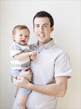 Father and baby boy (6-11 months) posing for portrait. 
Photo : Jessica Peterson