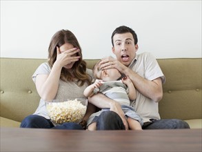 Young couple with baby boy (6-11 months) watching horror film . 
Photo: Jessica Peterson