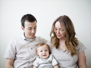 Young couple with baby boy (6-11 months) sitting on sofa. 
Photo: Jessica Peterson