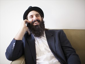 Happy bearded young man sitting on sofa. 
Photo: Jessica Peterson