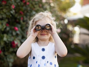 Young girl (4-5) looking through binoculars. 
Photo : Jessica Peterson