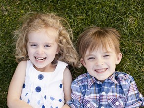 Outdoor portrait of girl (4-5) and boy (6-7) lying on grass. 
Photo : Jessica Peterson