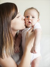 Mother kissing baby girl (2-5 months). 
Photo : Jessica Peterson