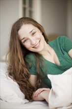 Happy young woman lying in bed. 
Photo: Jessica Peterson