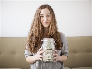 Young woman presenting her savings jar . 
Photo: Jessica Peterson