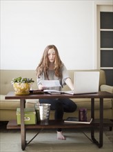 Young attractive woman using laptop while sitting on sofa. 
Photo : Jessica Peterson