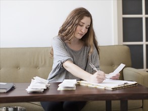 Young woman going though domestic paperwork. 
Photo: Jessica Peterson