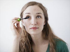 Attractive young woman applying mascara. 
Photo : Jessica Peterson