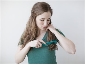 Attractive young woman combing hair. 
Photo: Jessica Peterson