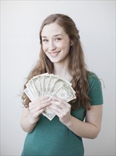 Attractive young woman holding fan made up from us dollar banknotes. 
Photo: Jessica Peterson