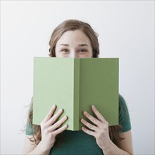 Happy young woman holding green book. 
Photo : Jessica Peterson