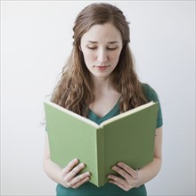 Happy young woman holding green book. 
Photo : Jessica Peterson