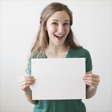 Portrait of young attractive woman holding blank sheet of paper. 
Photo: Jessica Peterson