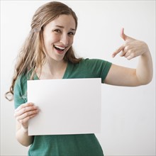 Portrait of young attractive woman holding blank sheet of paper. 
Photo: Jessica Peterson
