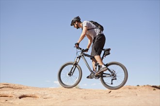 USA, Utah, Moab, Mid adult man riding mountain bicycle in remote scenery. 
Photo : Jessica