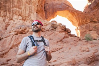 USA, Utah, Moab, Mid adult man posing in front of natural arches. 
Photo: Jessica Peterson
