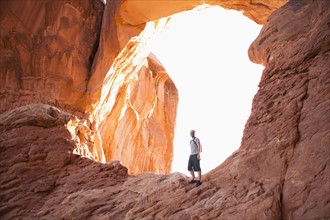 USA, Utah, Moab, Mid adult man posing in front of natural arches. 
Photo: Jessica Peterson