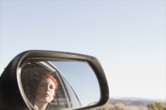 Young woman reflecting in car wing. 
Photo : Jessica Peterson