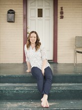 Portrait of happy young woman standing on porch. 
Photo : Jessica Peterson