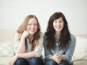 Two young female friends sitting on sofa. 
Photo : Jessica Peterson