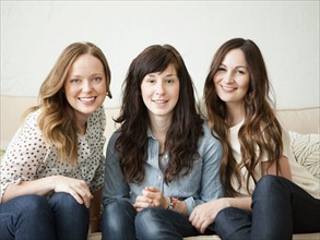 Three young female friends sitting on sofa. 
Photo : Jessica Peterson