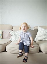 Toddler girl (2-3) sitting on sofa. 
Photo: Jessica Peterson