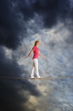 Woman walking on tightrope.