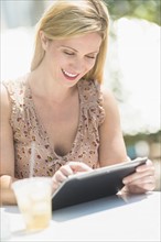 Woman using tablet pc at outdoor cafe table.