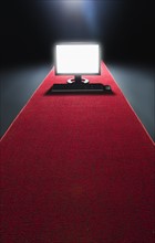 Studio shot of glowing computer on red carpet.