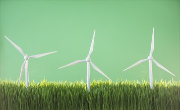Model wind turbines in grass on green background.