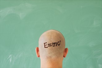 Man with formula on head in front of blackboard.