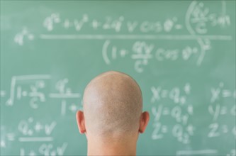 Man in front of blackboard with formulas.