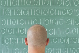Man in front of blackboard with binary code.