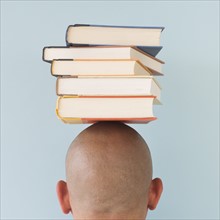 Studio shot of man with stack of books on head.