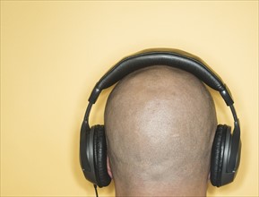 Back view of man with headphones on head.
