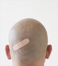 Back view of man with adhesive bandage on shaved head.