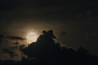Full moon emerging from clouds.