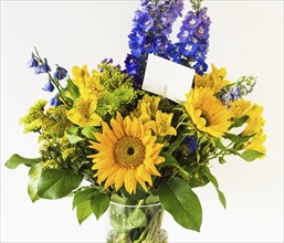 Bunch of colorful flowers in vase with note attached to it.